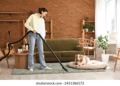 Pretty young woman using vacuum cleaner near cute Australian Shepherd dog at home - Powered by Shutterstock