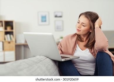 Pretty Young Woman Watching A Movie On Her Laptop Computer While Relaxing On The Couch In The Living Room.