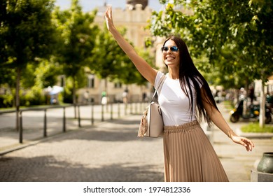 Pretty Young Woman Waving For A Taxi On The Street