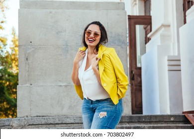 Pretty young woman wearing bright colorful jacket walking on the city street. Casual fashion, plus size model.