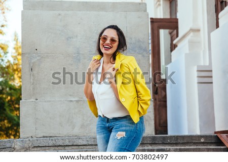 Pretty young woman wearing bright colorful jacket walking on the city street. Casual fashion, plus size model.