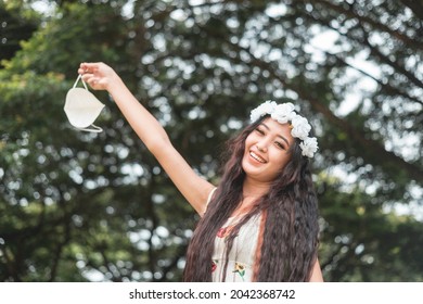 A Pretty Young Woman Wearing A Floral Headband Takes Off Her Face Mask. Happy And Relieved.