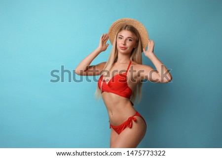 Pretty young woman wearing stylish bikini on blue background