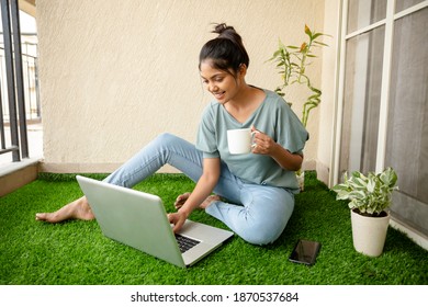 Pretty Young woman working on laptop at balcony artificial grass.