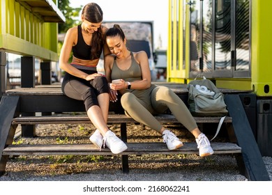 Pretty Young Women In Sportswear Looking At Mobile Phone After Exercise Training