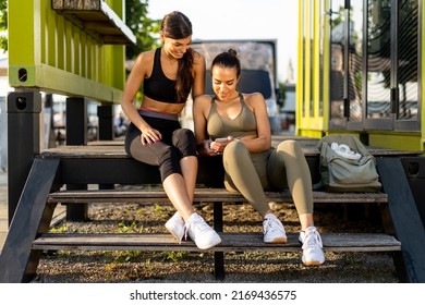 Pretty Young Women In Sportswear Looking At Mobile Phone After Exercise Training