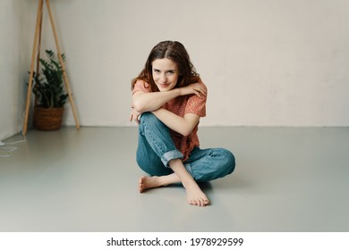 Pretty yung redhead woman relaxing barefoot on the floor with chin on hands looking at the camera with a sweet friendly smile and copyspace - Shutterstock ID 1978929599