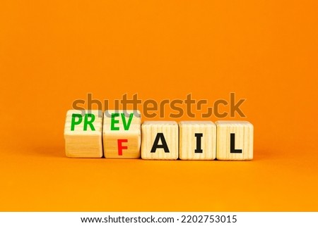 Prevail or fail symbol. Concept words Prevail or Fail on wooden cubes. Beautiful orange table orange background. Business prevail or fail concept. Copy space.