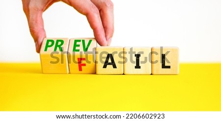 Prevail or fail symbol. Concept words Prevail or Fail on wooden cubes. Businessman hand. Beautiful yellow table white background. Business prevail or fail concept. Copy space.