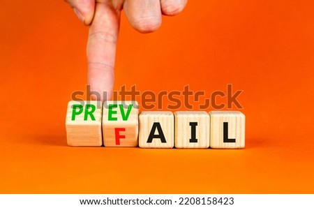 Prevail or fail symbol. Concept words Prevail or Fail on wooden cubes. Businessman hand. Beautiful orange table orange background. Business prevail or fail concept. Copy space.