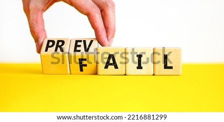 Prevail or fail symbol. Concept words Prevail or Fail on wooden cubes. Businessman hand. Beautiful yellow table white background. Business prevail or fail concept. Copy space.