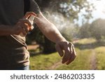 Prevention against mosquito bite during sunny summer day. Man is applying insect repellent on his hand.

