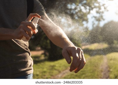 Prevention against mosquito bite during sunny summer day. Man is applying insect repellent on his hand.
