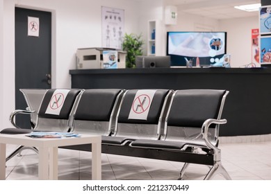 Prevention Posters Marking Waiting Chairs To Avoid Covid Infection. Empty Awaiting Room At Hospital Medical Office. Health Professional Department Unoccupied Reception Area.