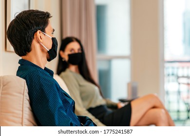 Prevention. Young Dark-haired Man Wearing Medical Mask, Sitting Indoors Together With His Girlfriend. Relationship, Dating, Coronavirus, Covid 19 Concept. Focus On Man. Horizontal Shot