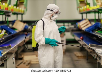 In the preventive isolated organic factory, a dedicated expert in a special protective uniform refreshes and cleans the air and space with a sprayer. COVID19 prevention, coronavirus control situation - Shutterstock ID 2048559716