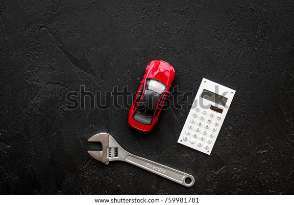 Price of car repair. Wrench\
near car toys and calculator on black background top view\
copyspace