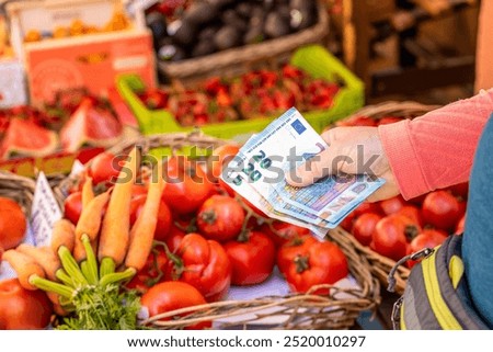 prices of fruit and vegetables in stores, A woman holds euro money in her hand against the background of a vegetable stand at a local market