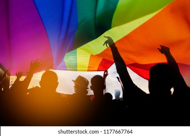 Pride Community At A Parade With Hands Raised And The LGBT Flag. 