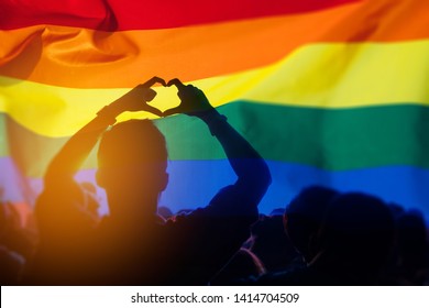 Pride Community At A Parade With Hands Raised And The LGBT Flag. 