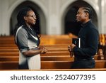 Priest attentively listens to a woman sharing her faith in a peaceful church setting, offering support and guidance in a moment of spiritual connection and empathy