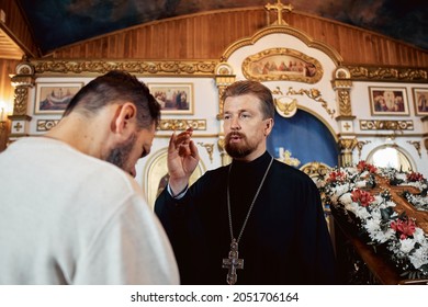 a priest blesses a bearded man in an Orthodox church after a festive church mass.