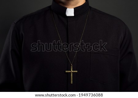 Priest with cross on black background, closeup