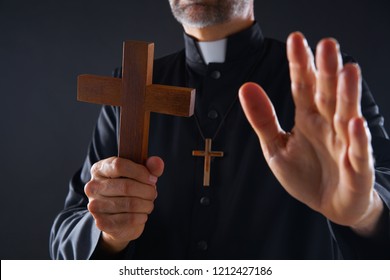 Priest holding cross of wood praying in foreground - Shutterstock ID 1212427186