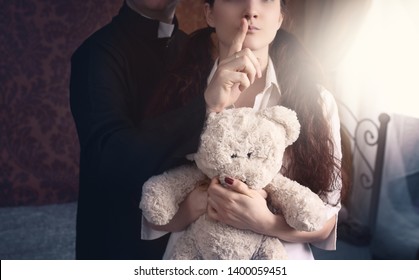 priest is holding a thumb on the lips of a young girl