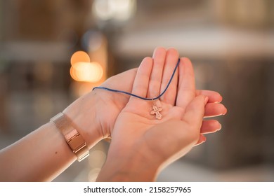 The priest holds a golden pectoral cross in his hands.
Golden cross close-up against the background of burning church candles.