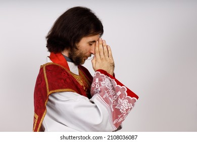 The priest keep hands folded in the pray. He wears traditional catholic liturgical clothes.