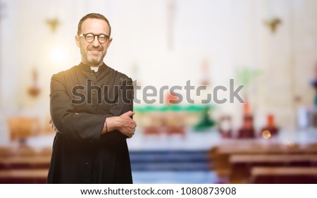 Priest religion man with crossed arms confident and happy with a big natural smile laughing at church