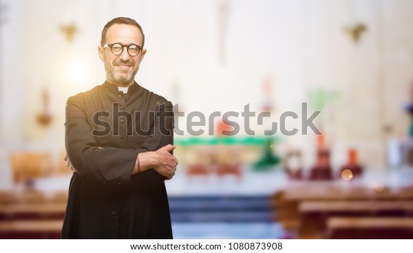 Priest religion man with\
crossed arms confident and happy with a big natural smile laughing\
at church