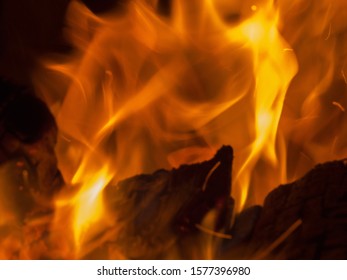 Primal bewitching magic of fire. Dance of orange flames on charred logs. Bonfire burning with crackling.