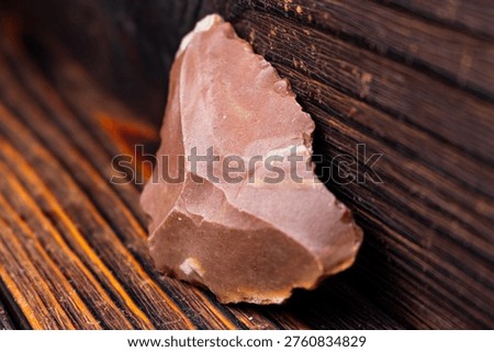 Primal flint scraper, an ancient Stone Age artifact, showcases early human craftsmanship. Primitive tool with rich history, on rustic wooden background
