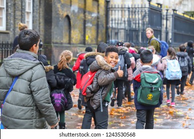 Primary Asian, Indian, Chinese   Caucasian Student Or Kids Carrying  School Bag On Their Way To Visit British Museum, City Of Westminster, London In Rain Winter Day, With Maple Leaves On Ground