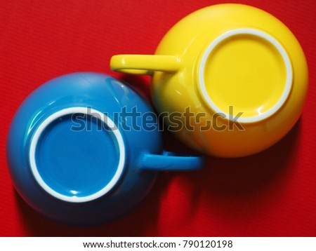 Primary colors concept red background with blue-yellow coffee cups. (Top view, close-up, selective focus)