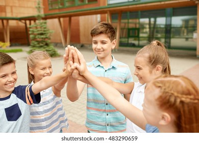 Primary Education, Friendship, Childhood And People Concept - Group Of Children Or Students Making High Five At School Yard