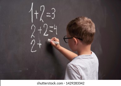 Primary Education. Rear View Of A Schoolboy Solves A Mathematical Example On A Blackboard In A Math Class.