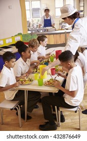 Primary School Kids Eat Lunch In School Cafeteria, Vertical