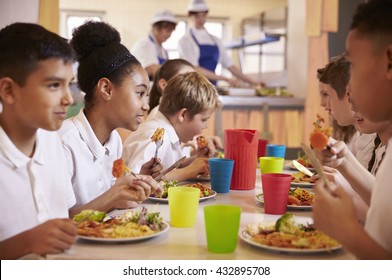 Primary school kids eat lunch in school cafeteria, close up