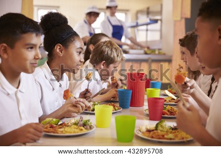 Primary school kids eat lunch in school cafeteria, close up