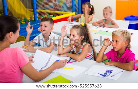 primary school kids sitting at school class and listening to a teacher at lesson 
