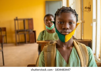 Primary School Pupil's Sitting In Class, Wearing Face Masks, And Observing Physical Distancing