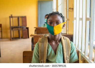 Primary School Pupil's Sitting In Class, Wearing Face Masks, And Observing Physical Distancing