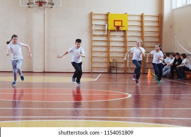 Primary School Students A Sport Lesson Indoors. Children Run And Play Mobile Games.