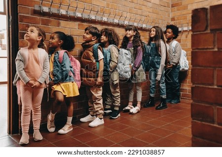 Primary school students waiting in line outside their classroom. Group of children eagerly waiting to start class in the morning. Elementary age kids standing together in school.