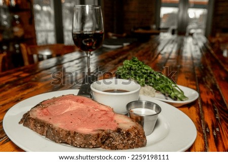 prime rib with broccolini and wine sitting on wood bar top