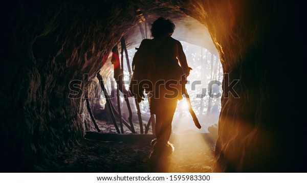 Primeval Caveman in Animal Skin and Fur Holds
Stone Tipped Spear Comes out of His Cave into Prehistoric Forest
Ready to Hunt. Neanderthal Going Hunting into the Jungle. Shot with
Warm Filter.