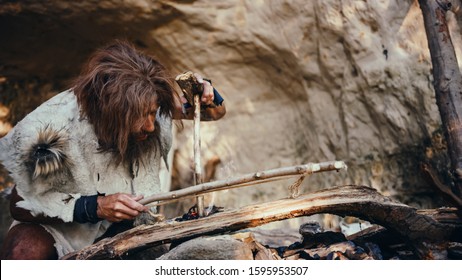 Primeval Caveman Wearing Animal Skin Trying to make a Fire with Bow Drill Method. Neanderthal Kindle First Man-Made fire in the Human Civilization History. Making Fire for Cooking.